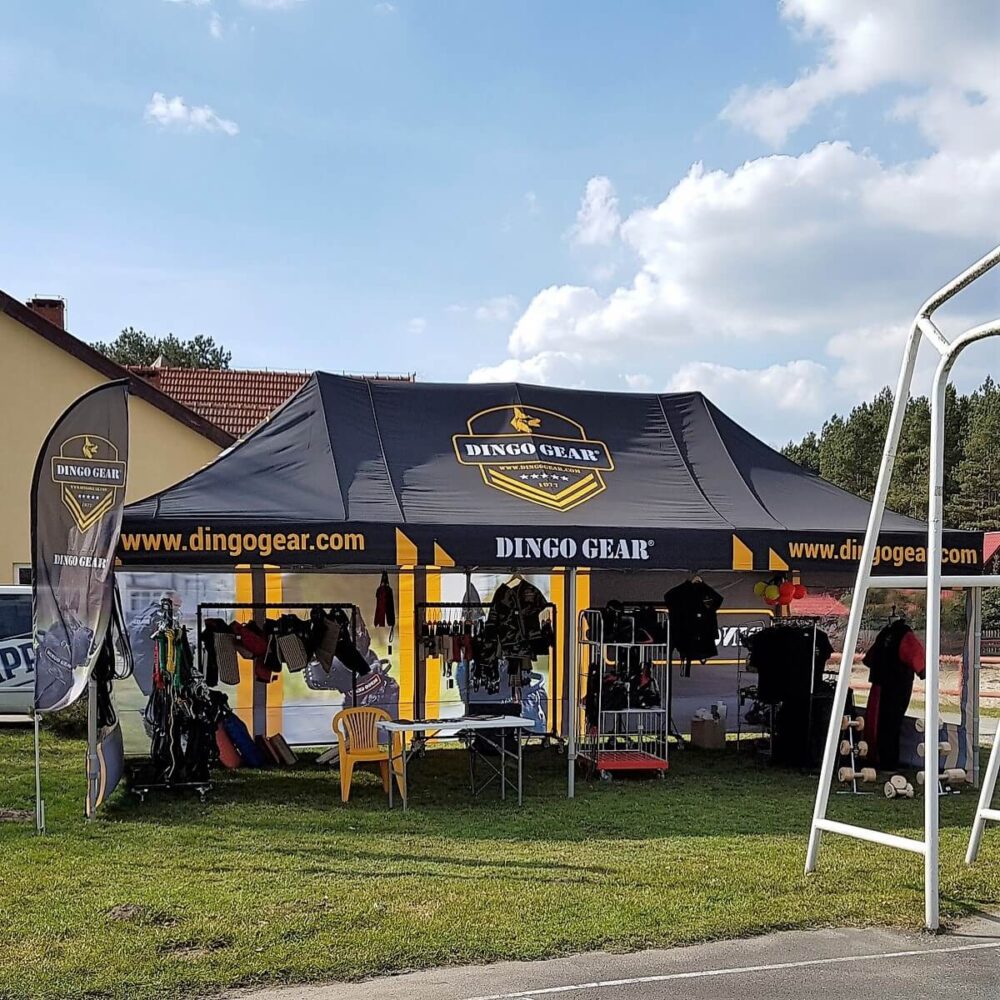Nůžkový stan 4x8 s potiskem Dingo Gear na venkovní akci.